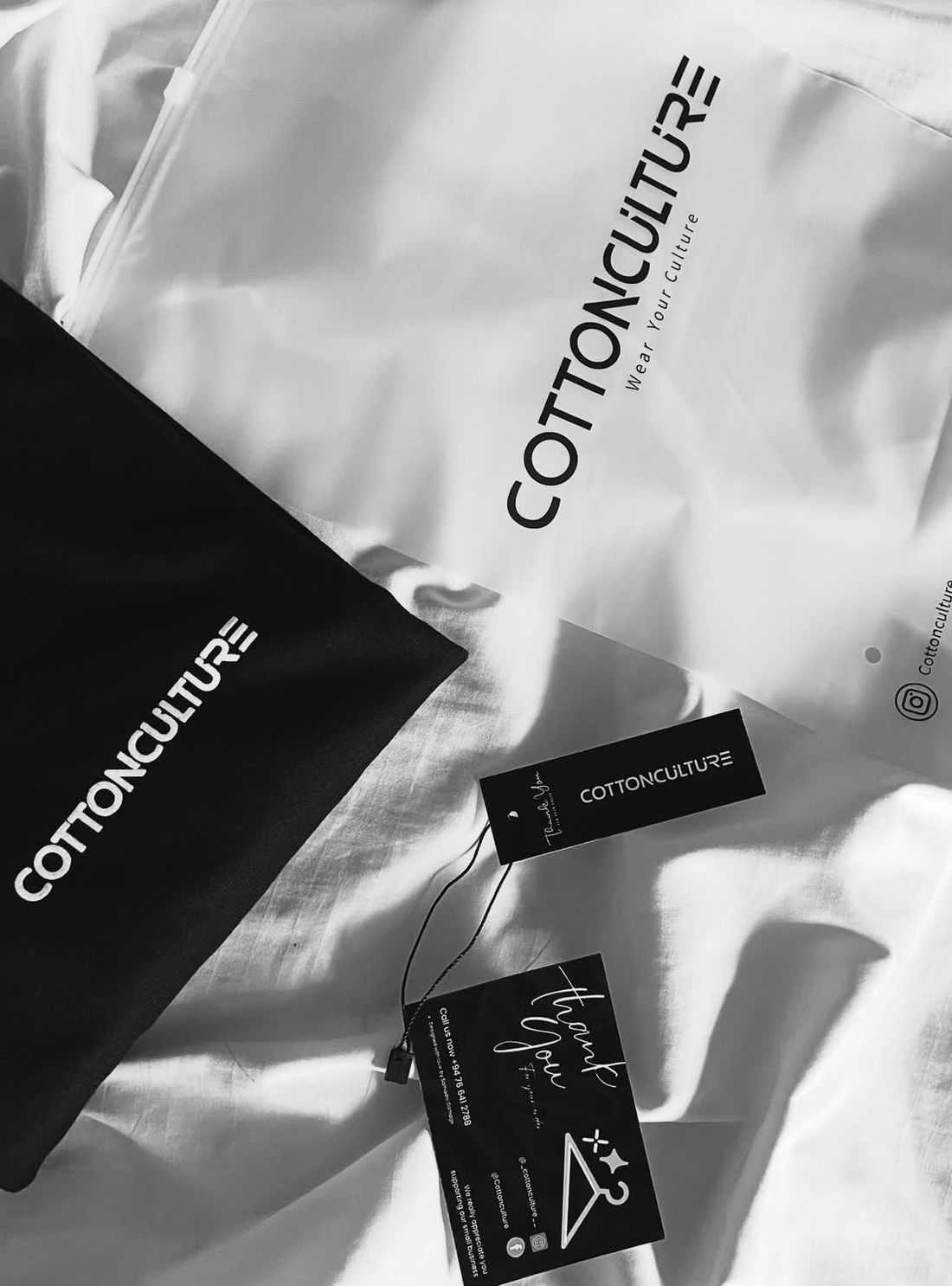 Frosted zip bag, dust bag, hang tag and thank-you card laid out on a white tee